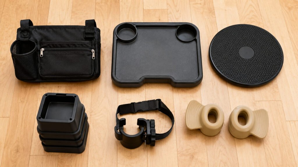 Best daily mobility accessories for seniors arranged on a light wood surface — a black walker bag with cup holder, a folding walker tray, a black pivot transfer disc, a set of black bed risers, a clip-on cane holder, and a pair of beige silicone doorknob grips