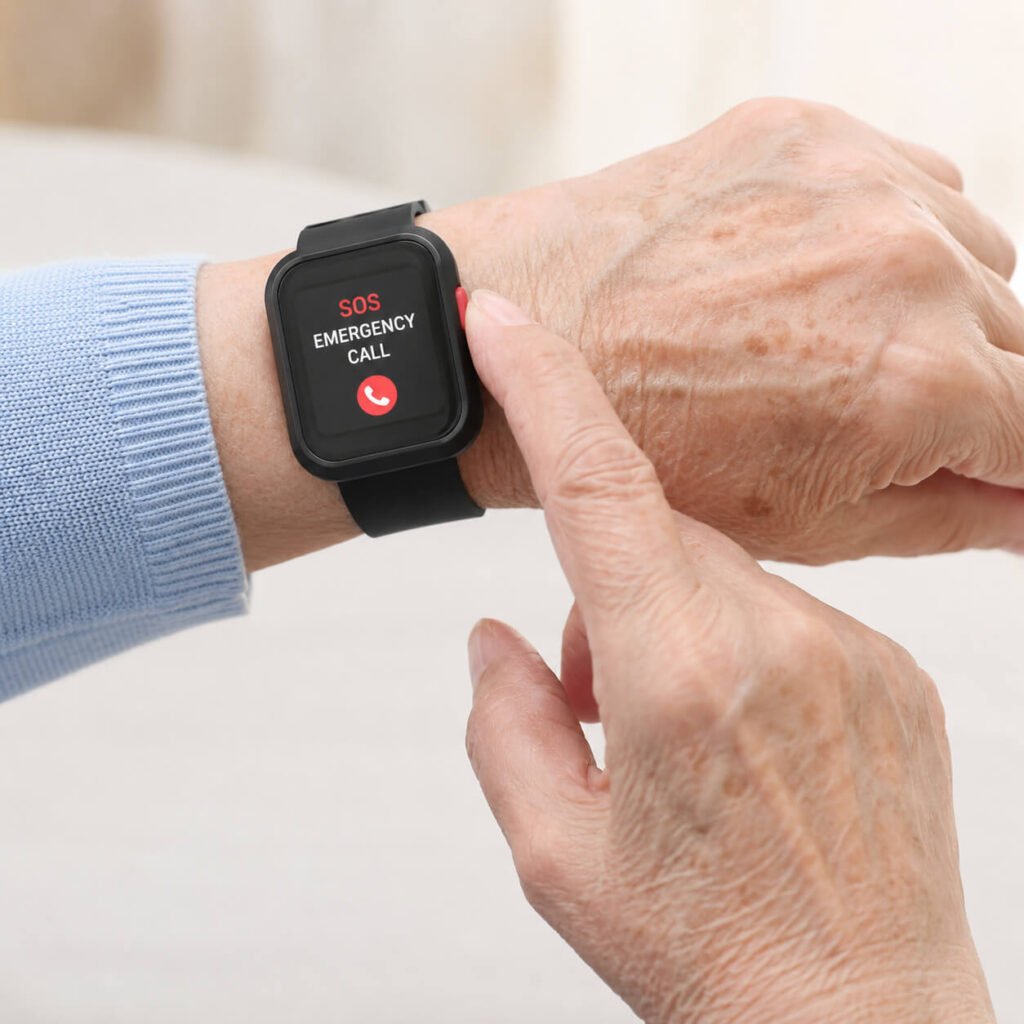 Close-up of a senior woman's hand pressing the red SOS button on a black medical alert smartwatch on her wrist