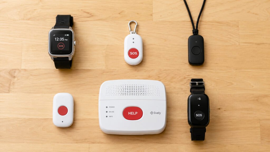  Emergency alert devices for seniors arranged on a clean white surface — a black smartwatch, a red SOS pendant on a black lanyard, a white mobile alert button, and a landline base station unit